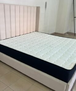 Modern bedroom with a high, padded headboard in a longitudinal design, and a mattress.