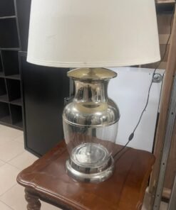 A table lamp from Marina Home, featuring a glass and metal base with a fabric shade.