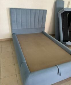 A modern bed with a padded headboard and in a blue color, usually featuring a smart storage system under the mattress to provide extra space.