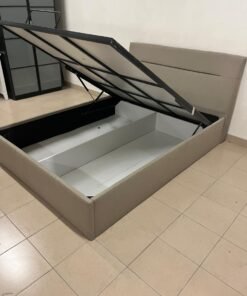 Beige upholstered bed with a hydraulic storage mechanism for raising the mattress.