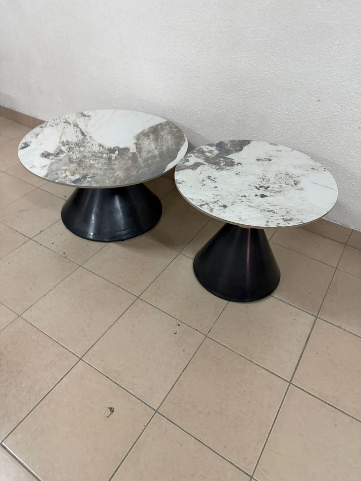 This is a round coffee table with a marble top and a black metal base in a modern design.
