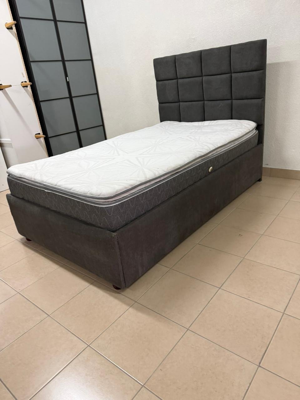 A modern single bed featuring a padded headboard