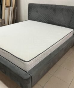 This bed is upholstered in grey velvet paint and features a geometrically designed, padded headboard.
