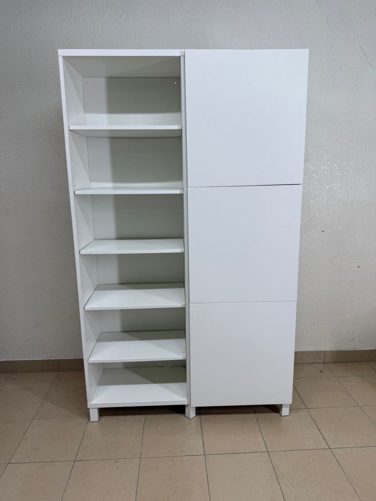 A white storage cabinet from IKEA, model BESTÅ, comes with open units and closed fronts.