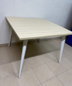 A dining table or desk with a modern design and slanted white legs.