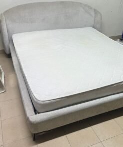 An upholstered bed with a high, curved headboard.