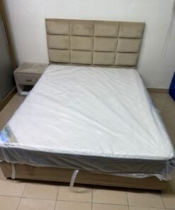 The beige upholstered bed features a checkered, padded headboard and comes with a new mattress.