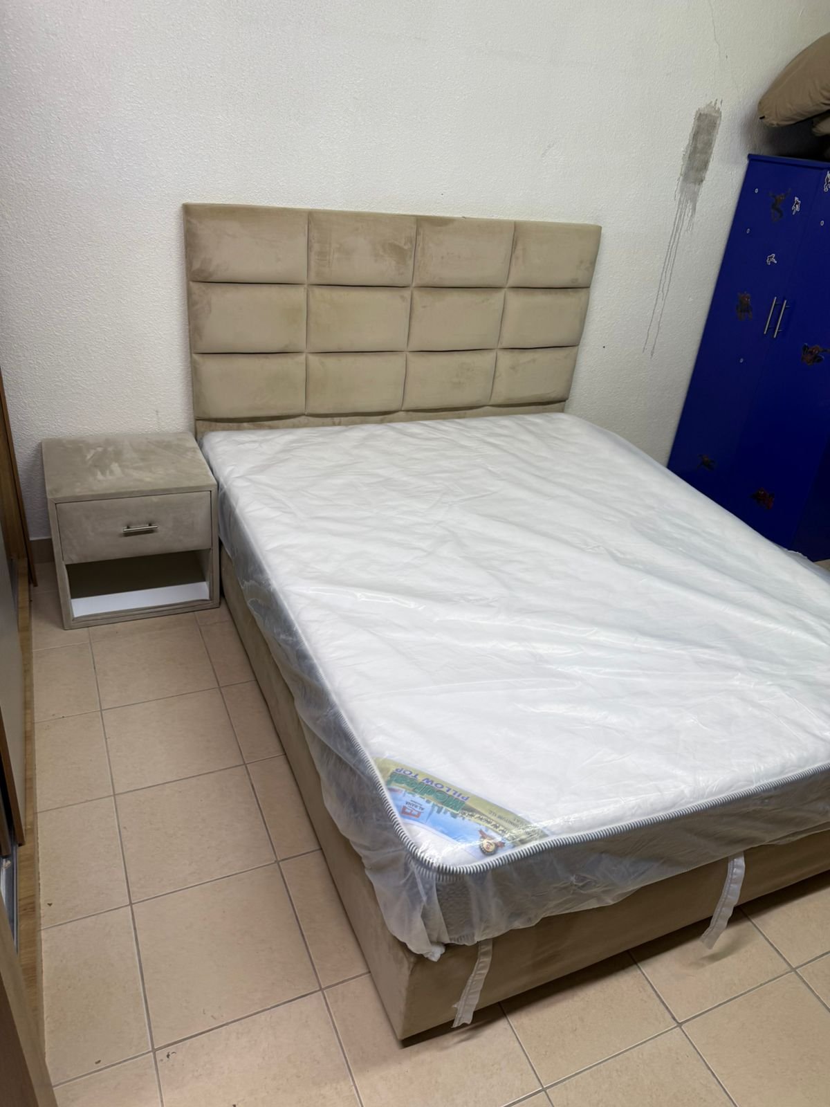 The beige upholstered bed features a checkered, padded headboard and comes with a new mattress. - Image 5