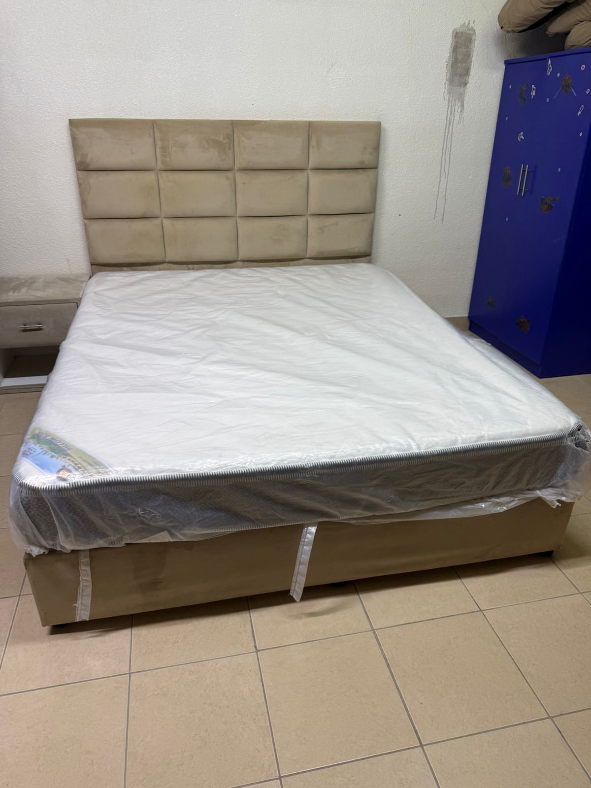 The beige upholstered bed features a checkered, padded headboard and comes with a new mattress. - Image 6