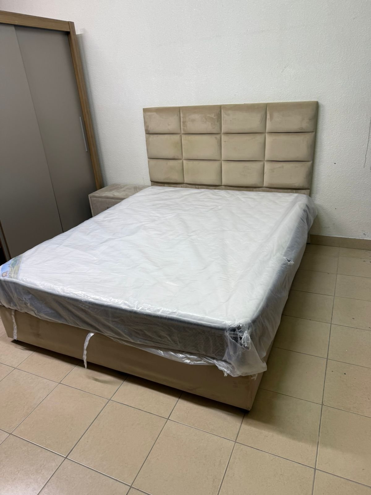 The beige upholstered bed features a checkered, padded headboard and comes with a new mattress. - Image 4