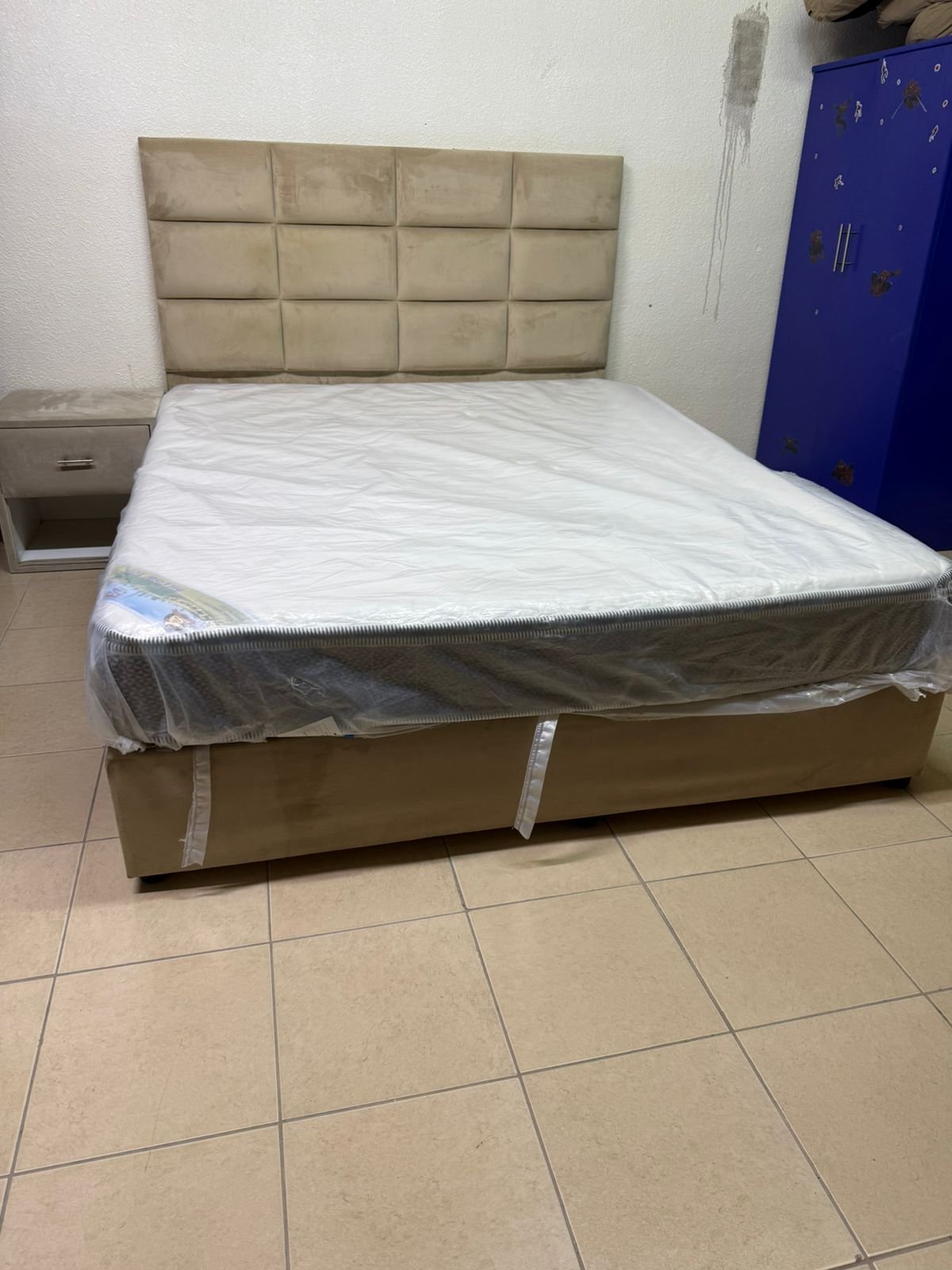 The beige upholstered bed features a checkered, padded headboard and comes with a new mattress. - Image 7