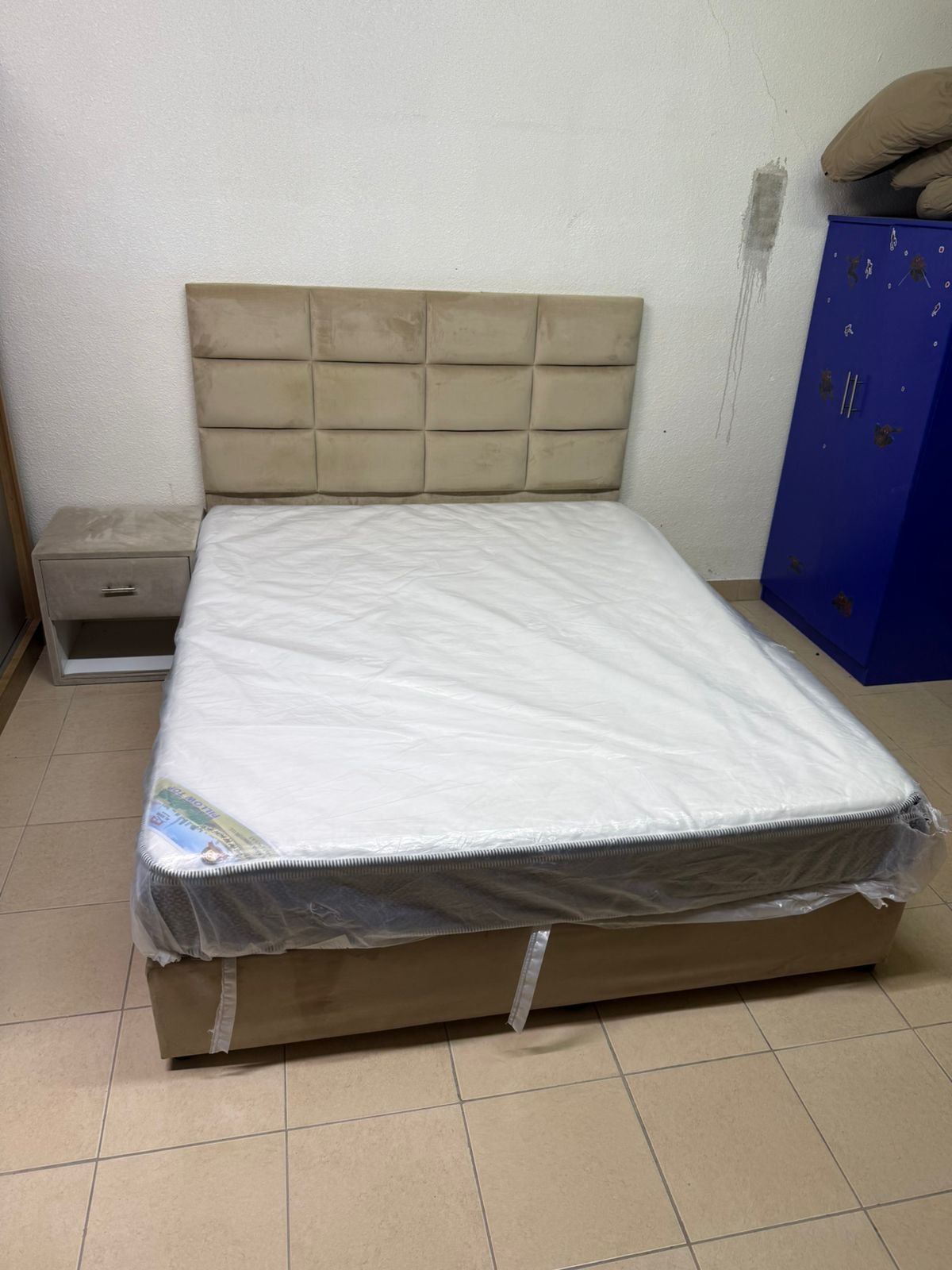 The beige upholstered bed features a checkered, padded headboard and comes with a new mattress. - Image 2