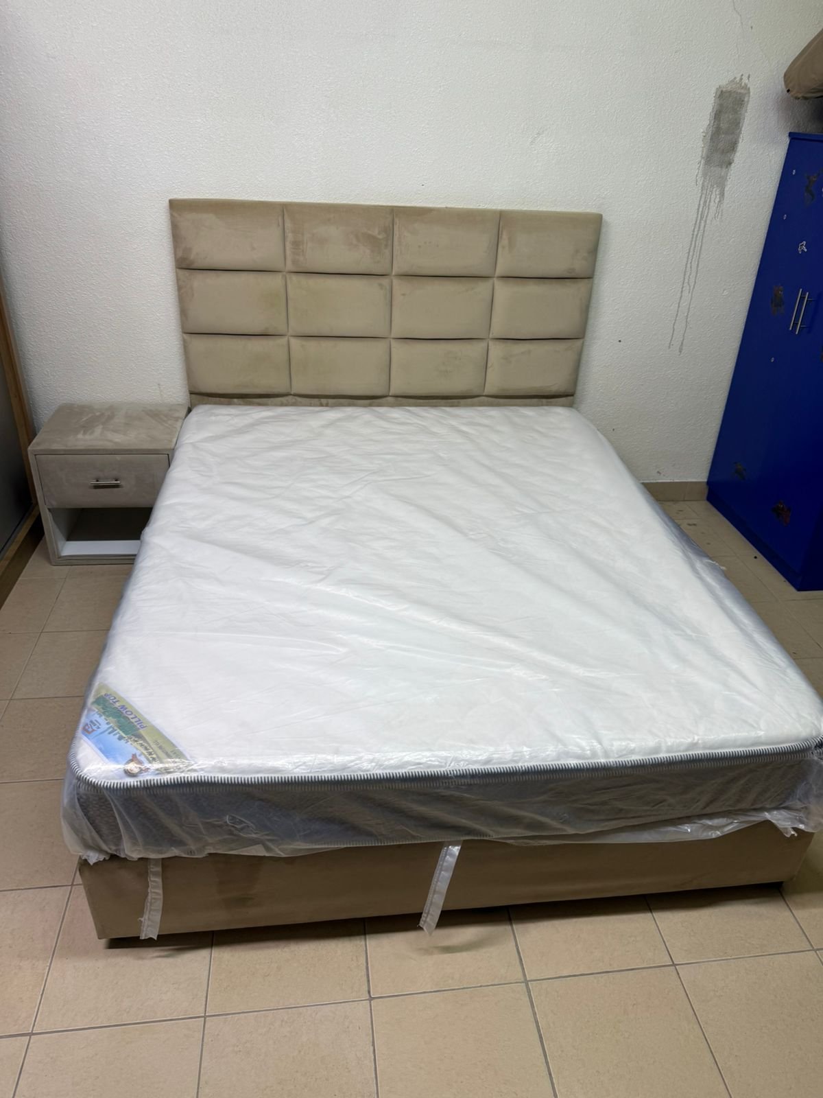 The beige upholstered bed features a checkered, padded headboard and comes with a new mattress. - Image 3