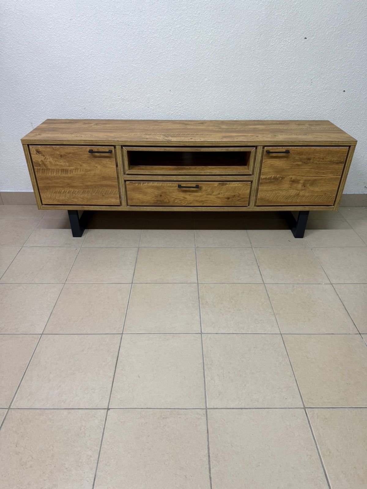 This modern TV unit features a warm beige wood finish and sturdy black metal legs.