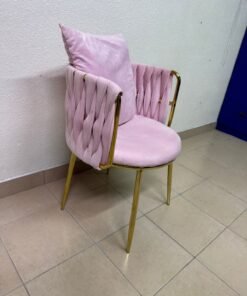 The pink velvet chair features a modern design with a woven back and an elegant gold metal base.