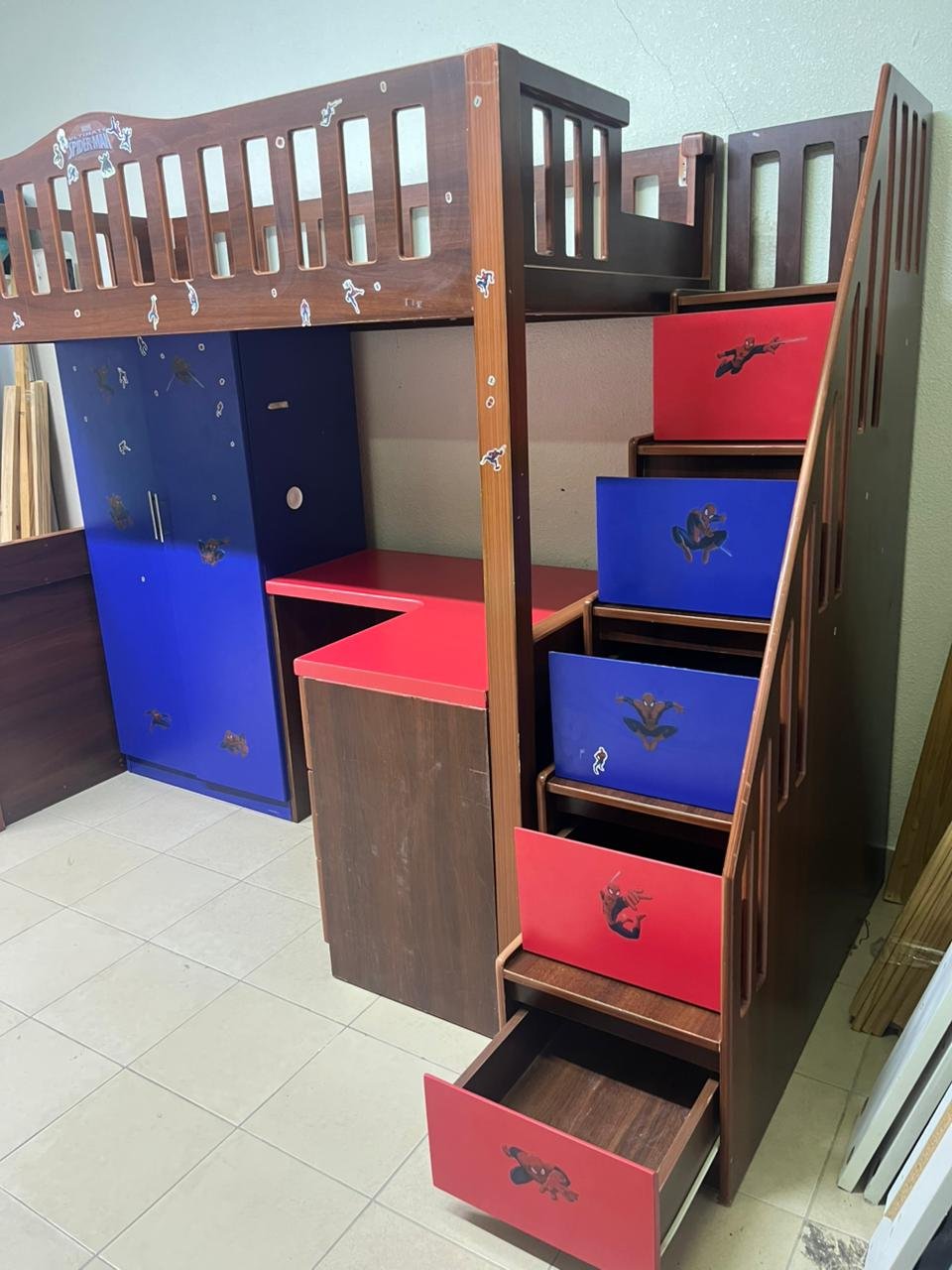 A multi-functional Spider-Man-themed loft bed for children, including a wardrobe, study desk, and stairs with drawers.