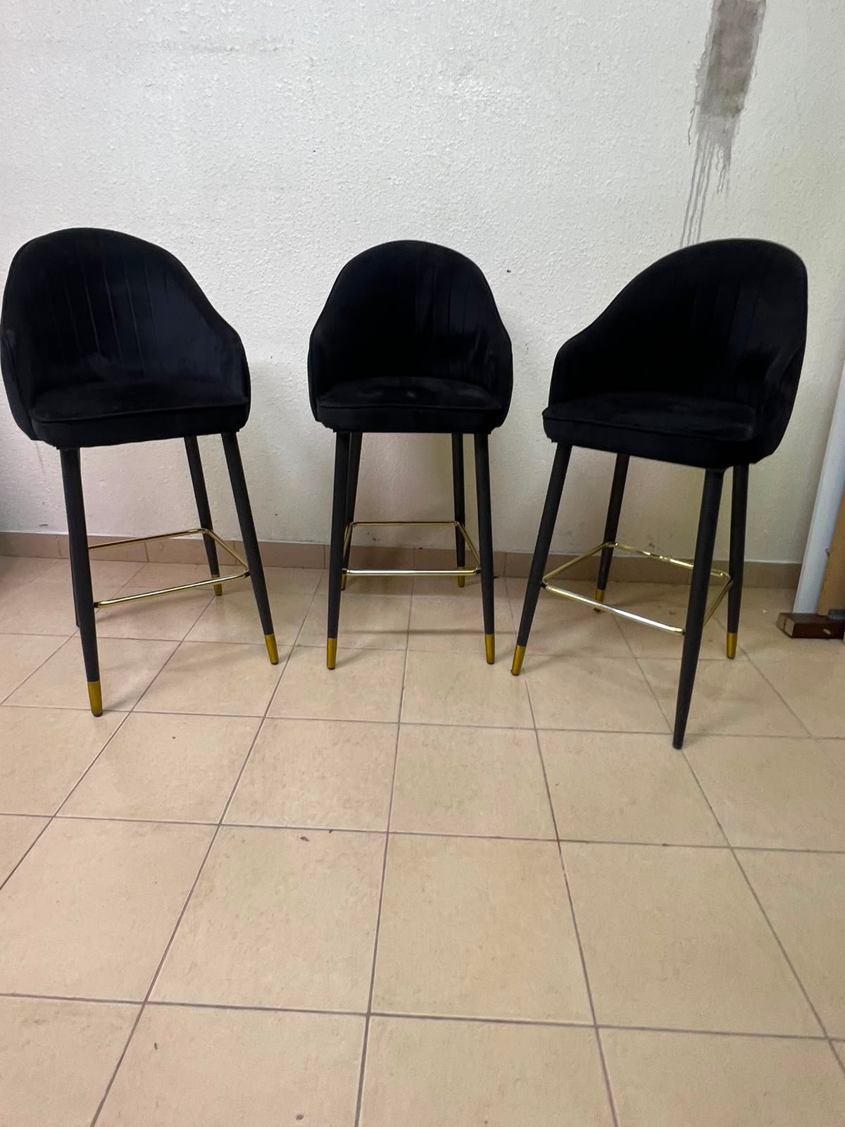 This black velvet bar stool from TUKA features a round design and black legs with gold accents.