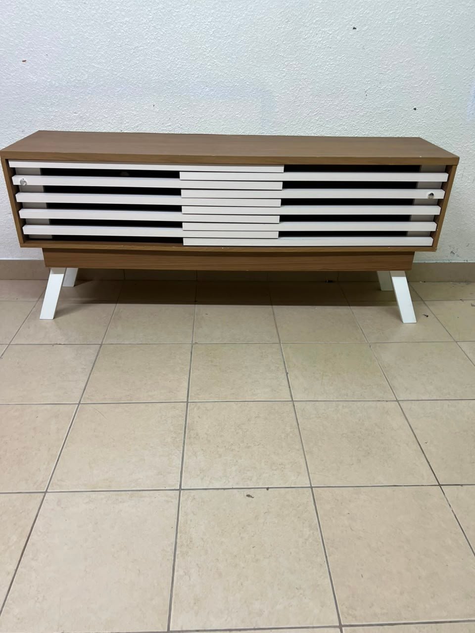The "Reflekt" TV unit from "Pan Emirates" features a brown wood design with white sliding doors for a modern touch.