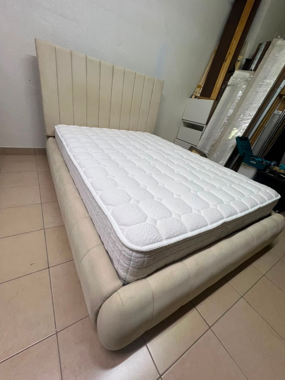 The cream-colored upholstered bed features a stylish and comfortable headboard. - Image 6