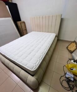 The cream-colored upholstered bed features a stylish and comfortable headboard.