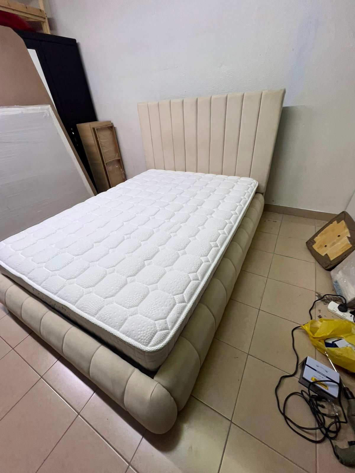 The cream-colored upholstered bed features a stylish and comfortable headboard.