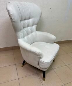 This wingback chair from AD CORE features white upholstery and a tufted back.