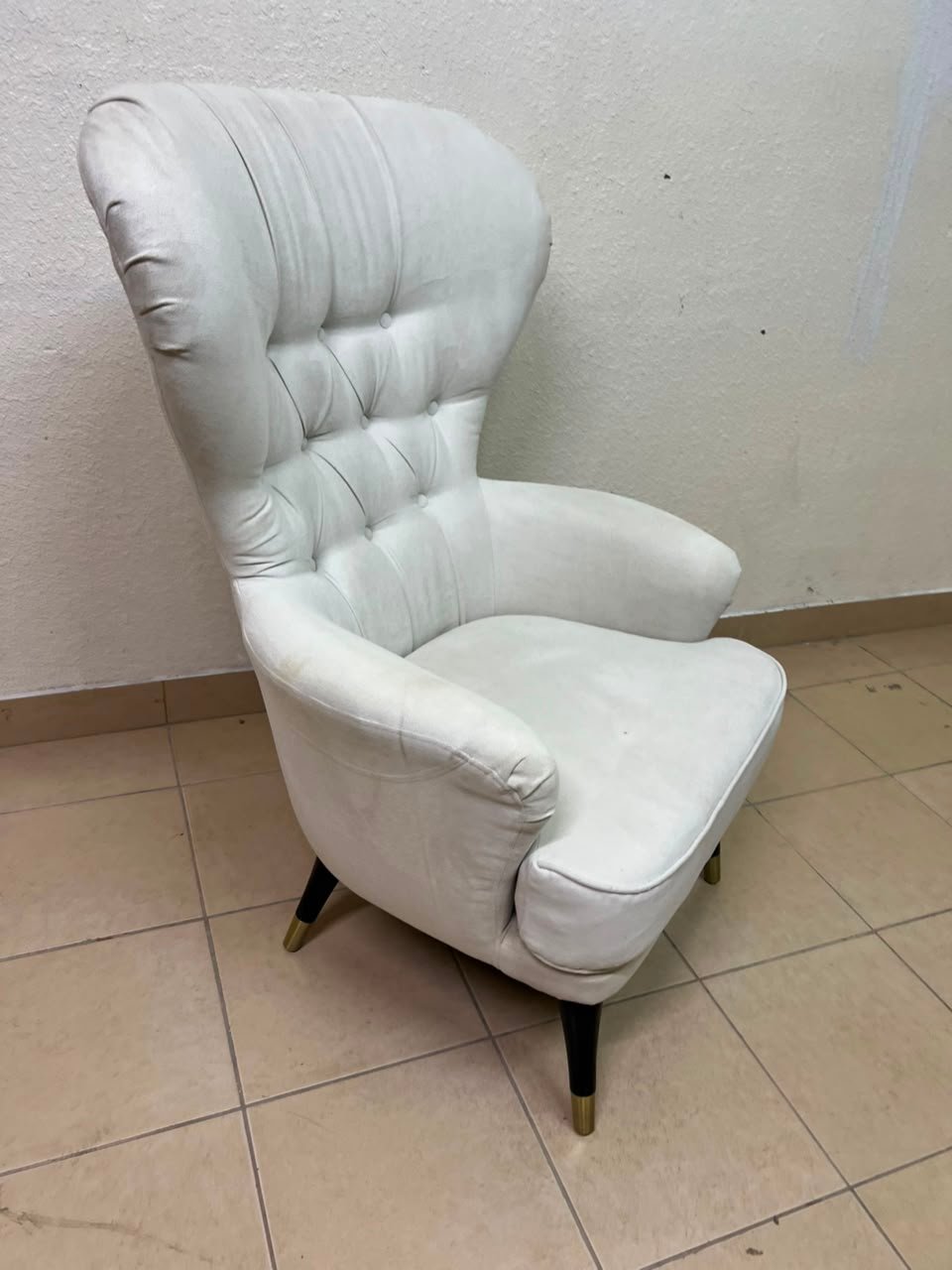 This wingback chair from AD CORE features white upholstery and a tufted back.