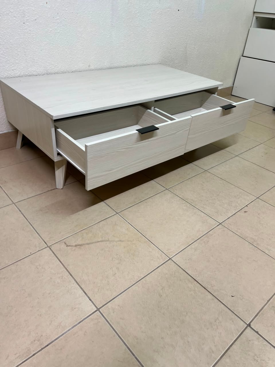 The white Wayne coffee table from Home Centre features two spacious drawers with black handles. - Image 8