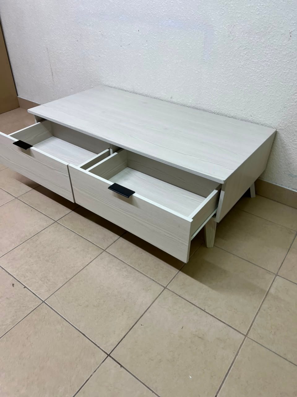 The white Wayne coffee table from Home Centre features two spacious drawers with black handles. - Image 12