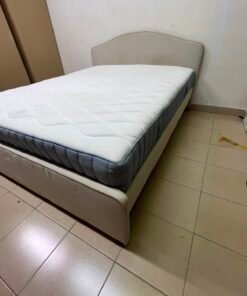 A bed from IKEA featuring a curved headboard and a beige upholstered base.