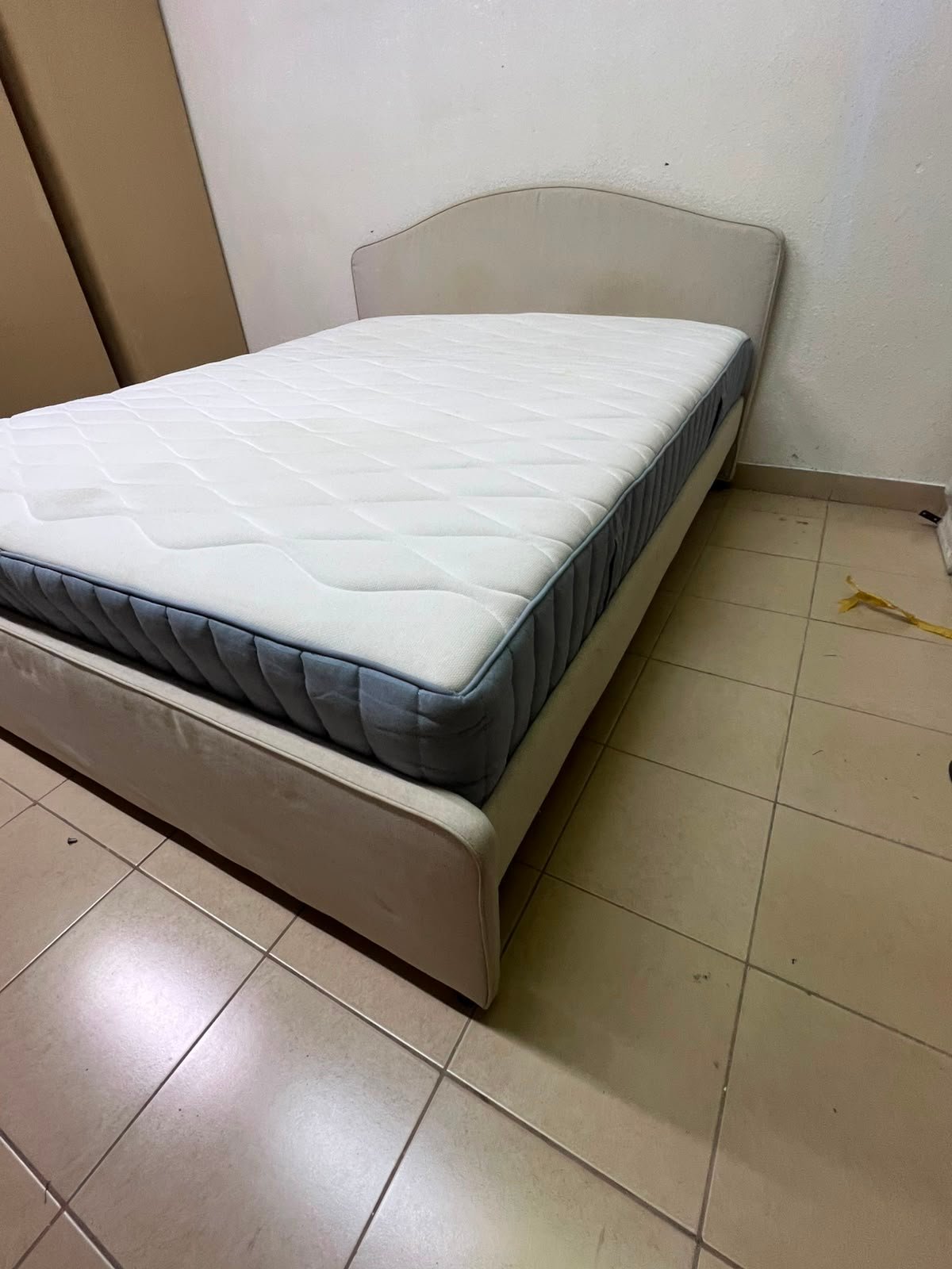 A bed from IKEA featuring a curved headboard and a beige upholstered base.