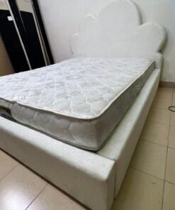 A fully upholstered white frame bed featuring a unique cloud-shaped headboard design.