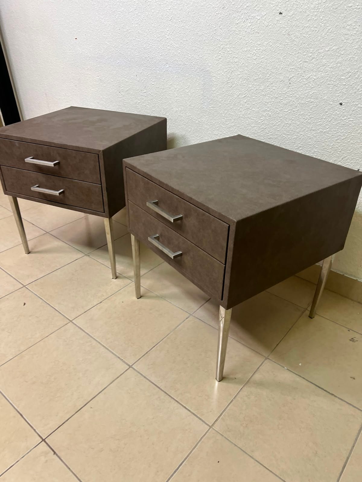 A brown bedside table with a leather or suede-like finish, featuring silver drawers and handles, similar to those found at Wayfair.