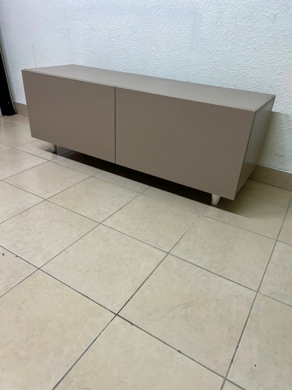 The TV cabinet features a calm beige color and a simple, modern design.
