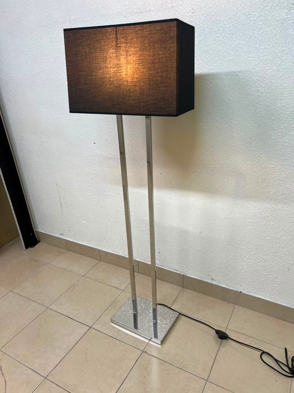 This modern floor lamp features a chrome-plated metal frame and a black fabric cover. - Image 3