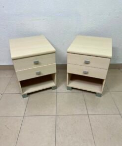 A set of two modern bedside tables in a light wood color with two drawers and open storage space.