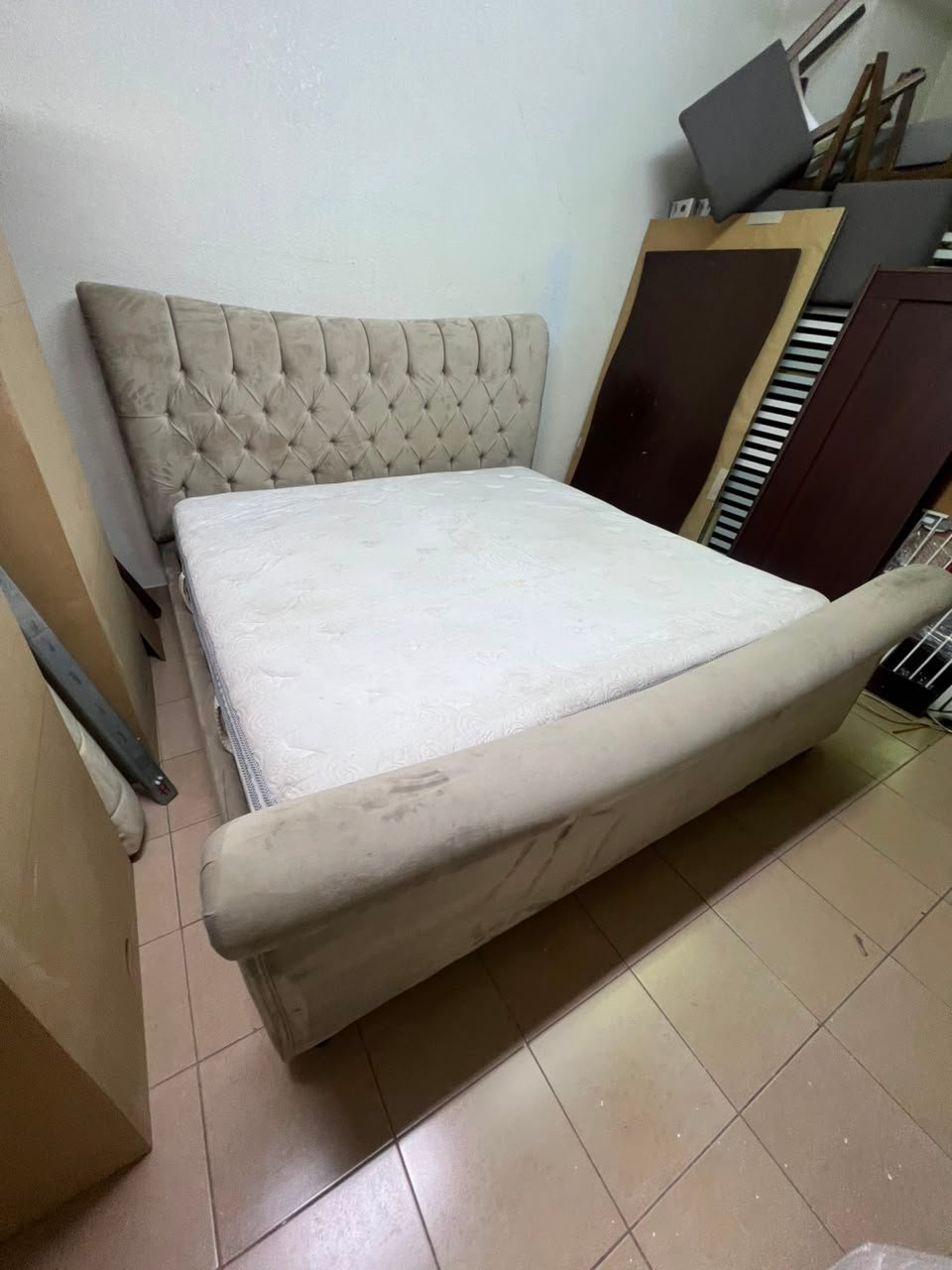 A classic diamond-patterned quilted bed with a mattress featuring soft velvet fabric in beige or gray.
