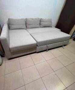 The IKEA FRIHETEN corner sofa that converts into a bed features a light gray color and a practical design that includes storage space.