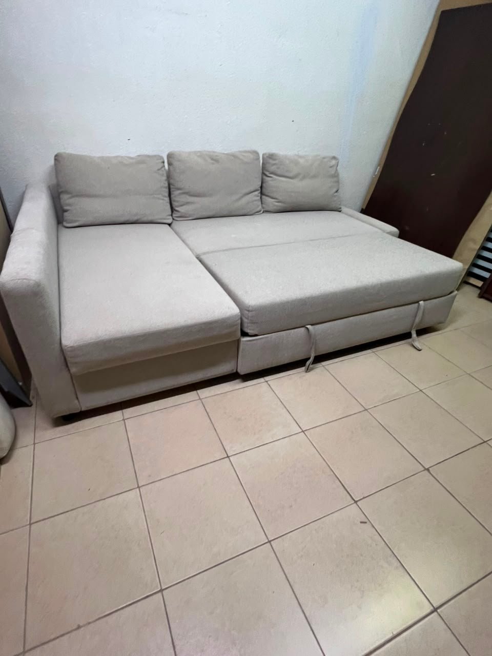 The IKEA FRIHETEN corner sofa that converts into a bed features a light gray color and a practical design that includes storage space.