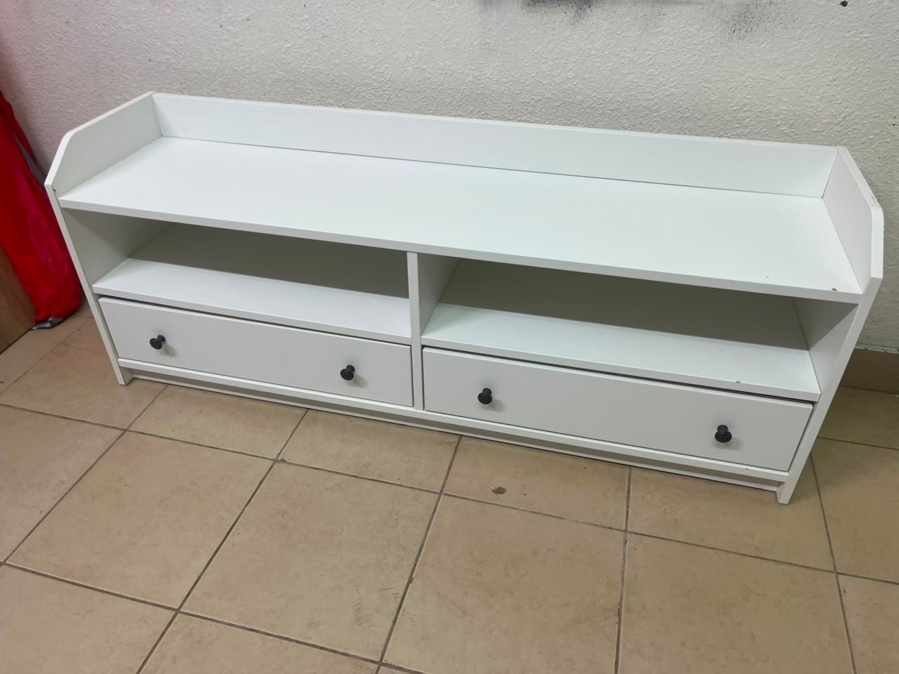 The IKEA HAUGA TV stand in white features a classic design with two drawers and open spaces.