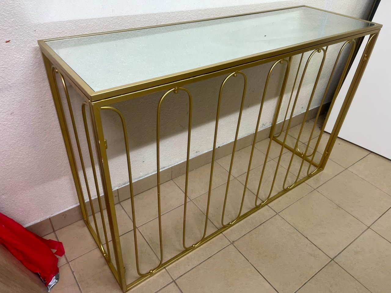Modern console table with a gold metal frame and reflective glass top - Image 3