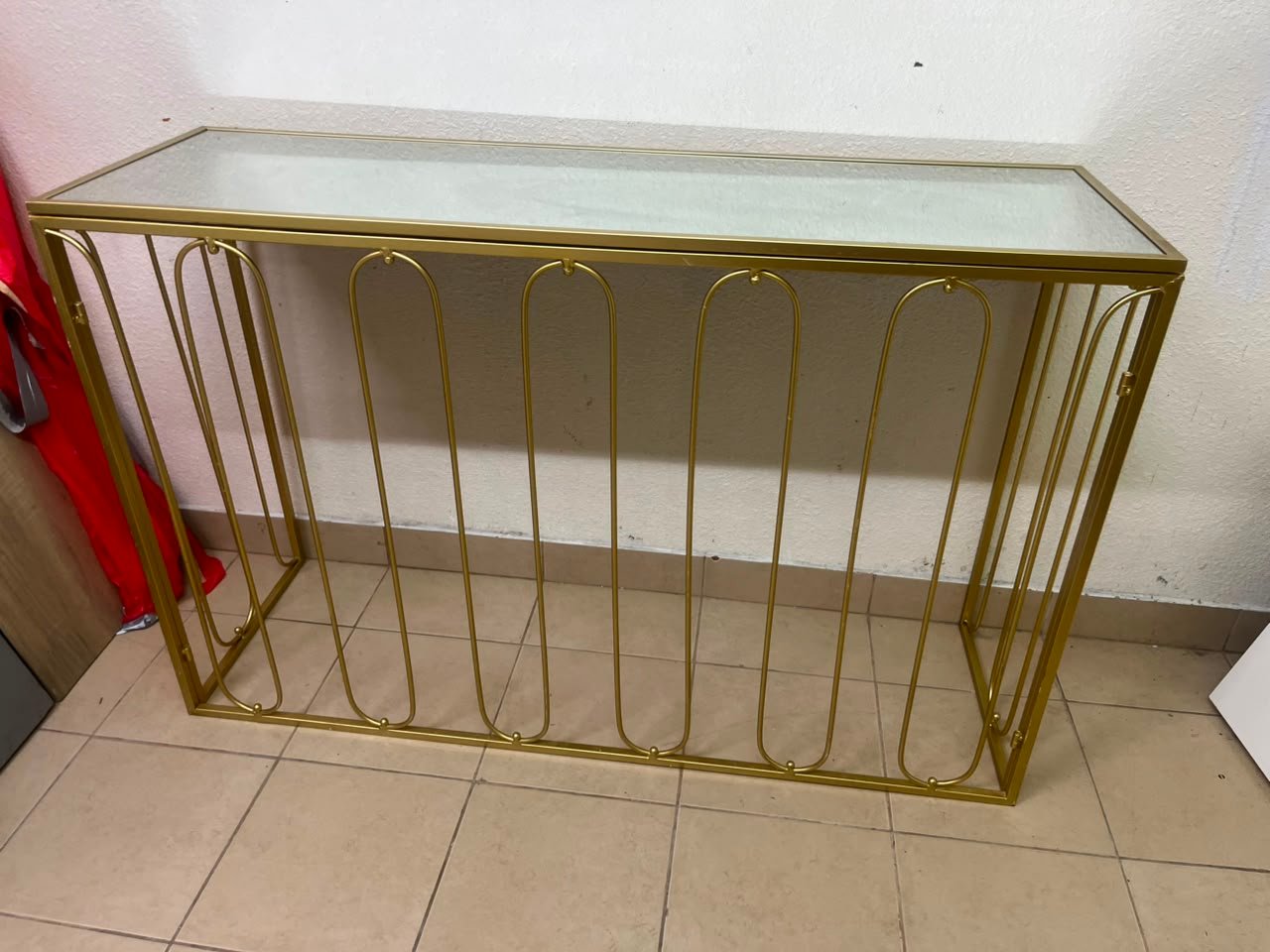 Modern console table with a gold metal frame and reflective glass top
