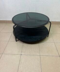 Where Saints Go's "Zenith" round coffee table with a dark glass top and black metal frame