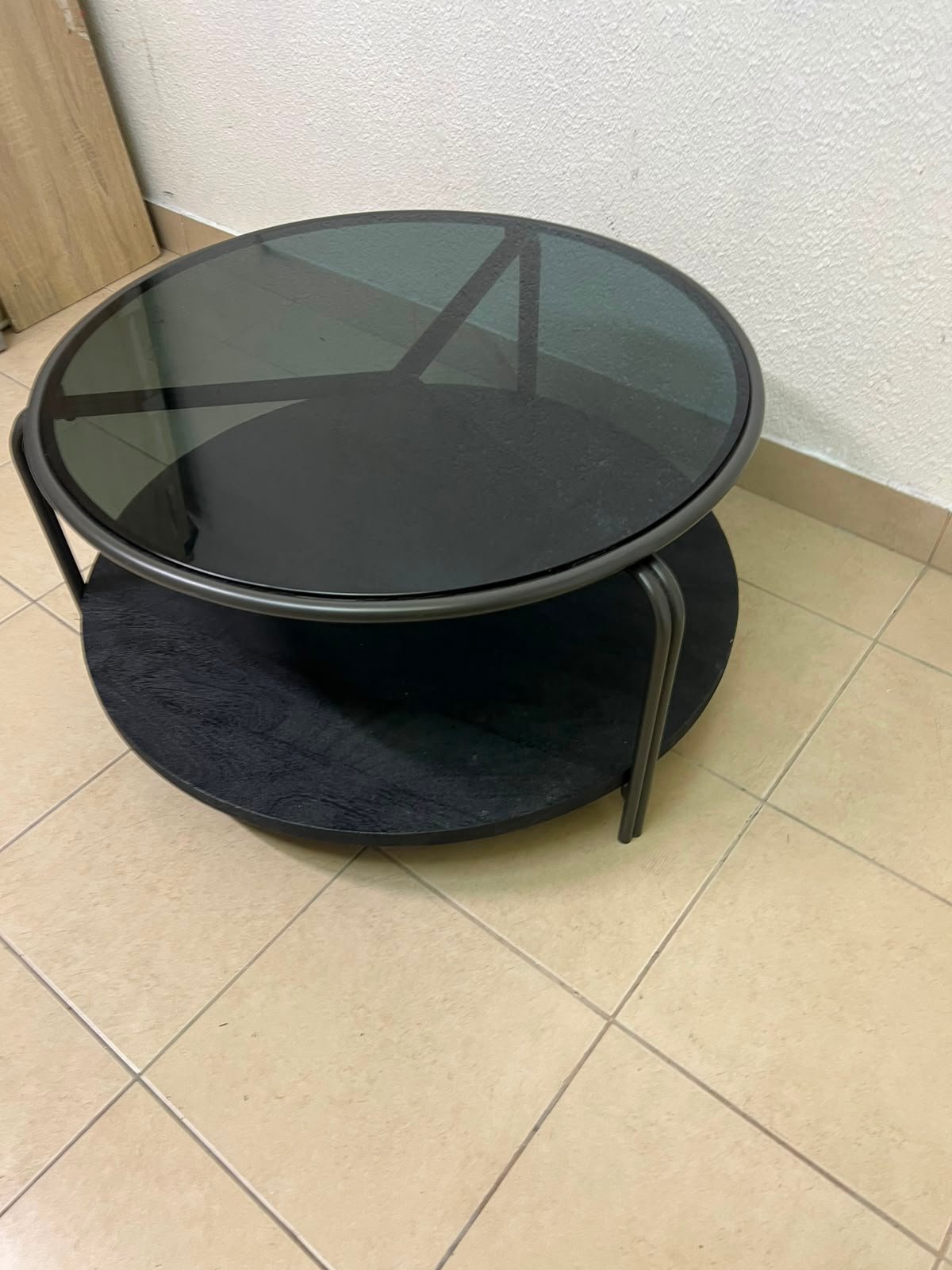 Where Saints Go's "Zenith" round coffee table with a dark glass top and black metal frame - Image 5