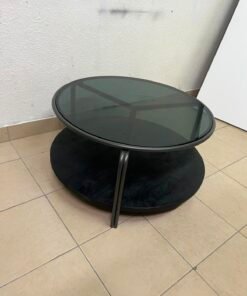 Where Saints Go's "Zenith" round coffee table with a dark glass top and black metal frame - Image 9