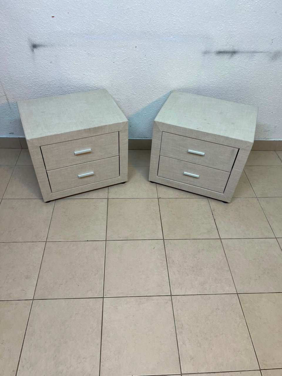A beige upholstered nightstand with two drawers and silver handles. - Image 7