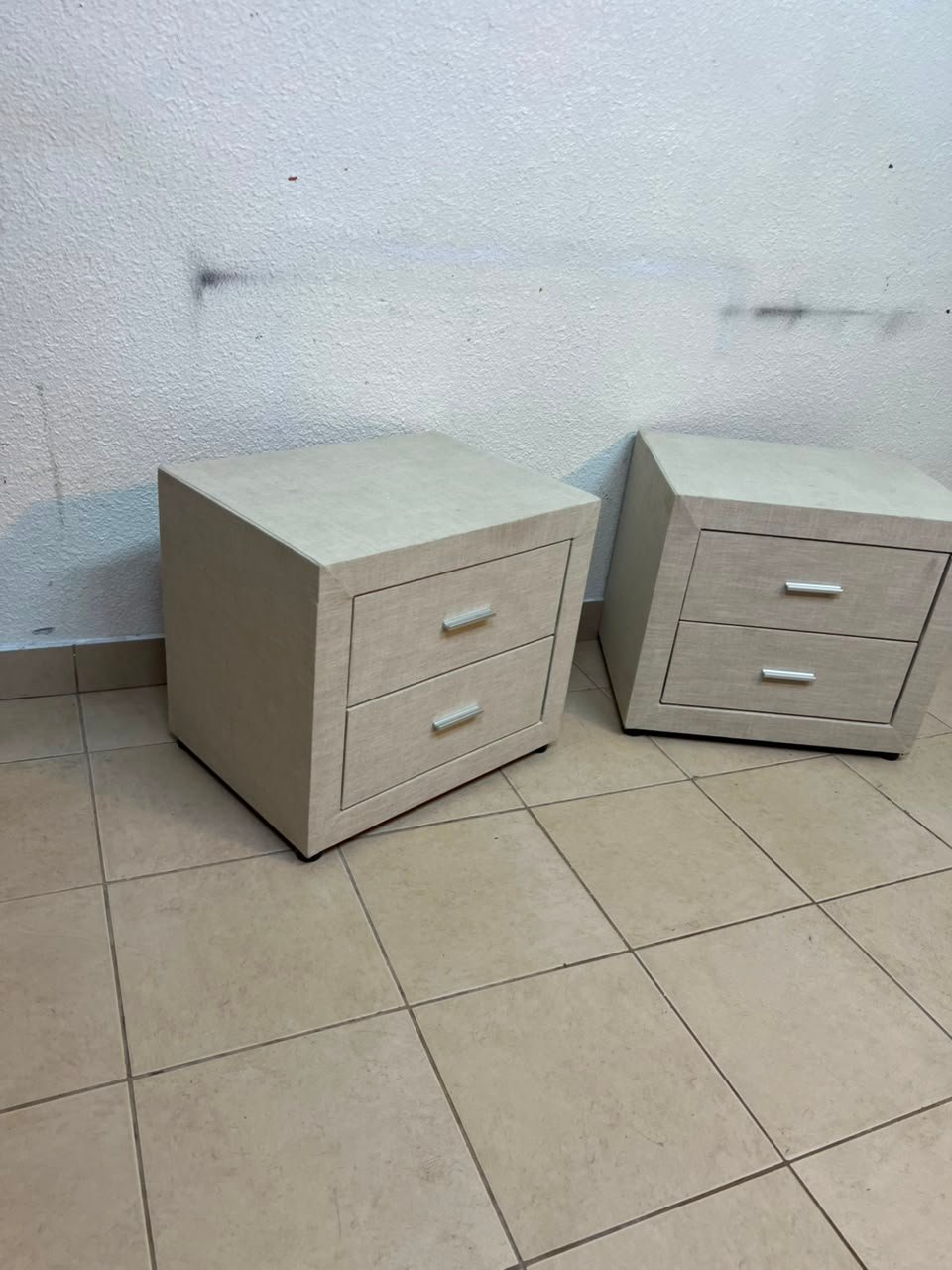 A beige upholstered nightstand with two drawers and silver handles. - Image 8