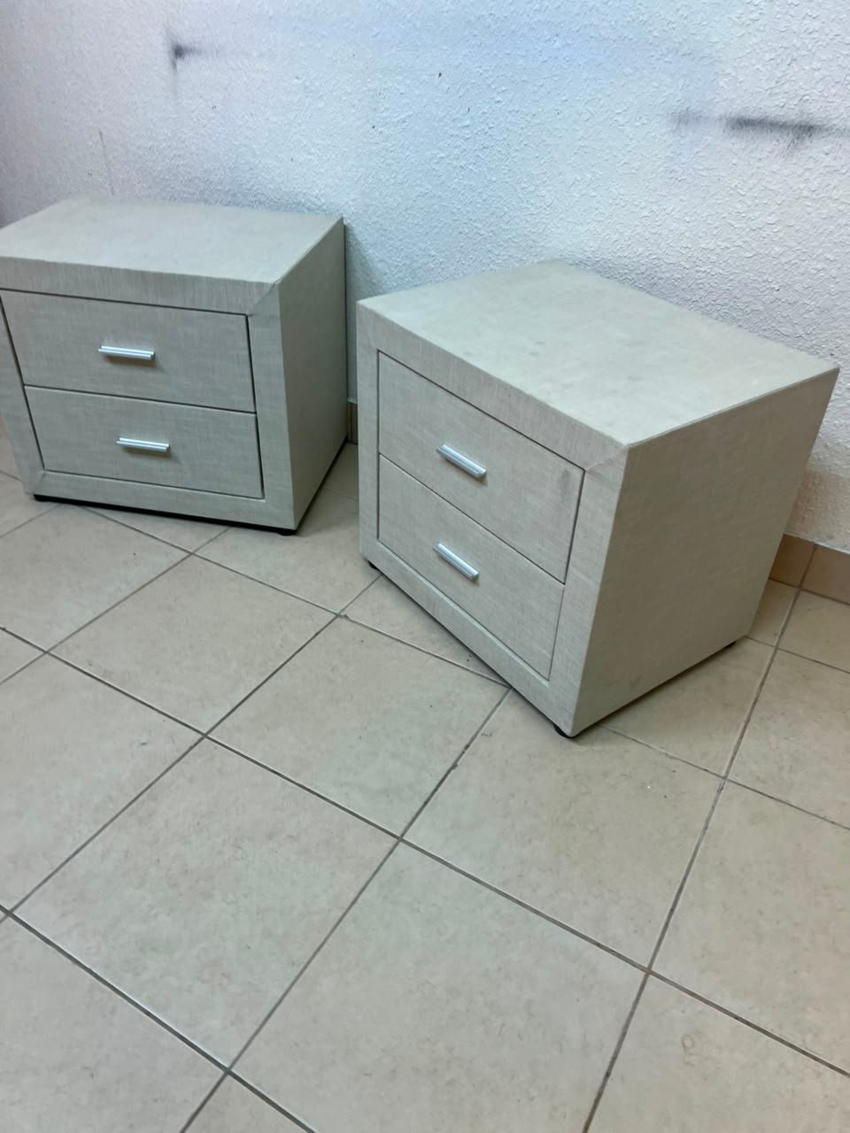 A beige upholstered nightstand with two drawers and silver handles. - Image 3
