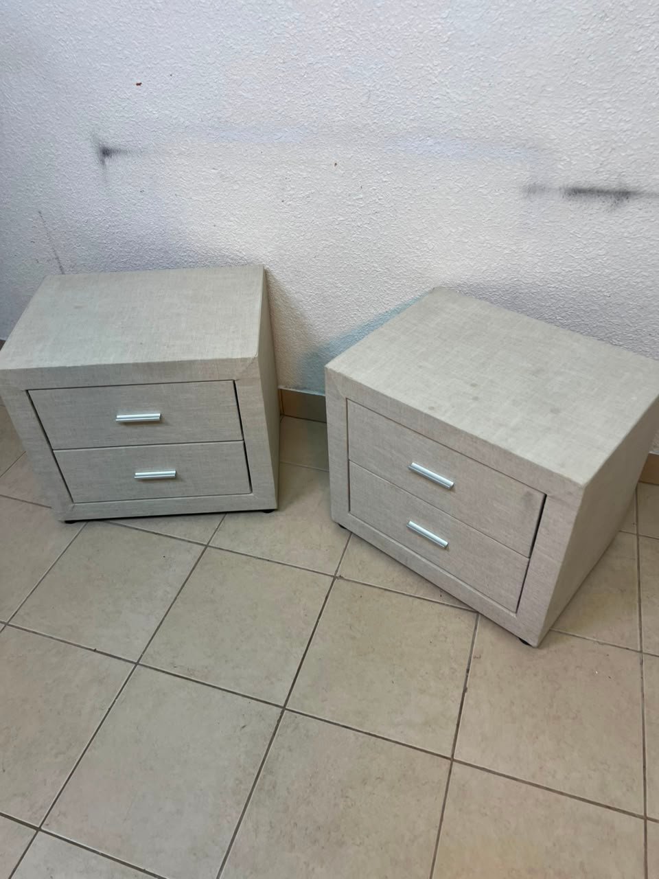 A beige upholstered nightstand with two drawers and silver handles. - Image 9