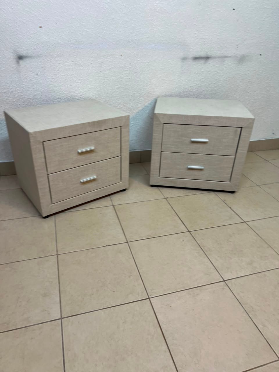 A beige upholstered nightstand with two drawers and silver handles. - Image 2